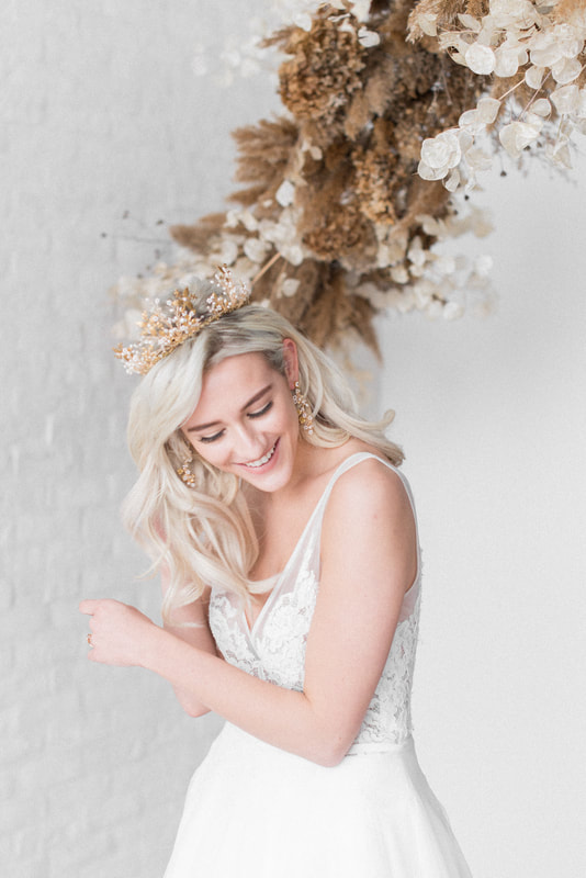 Laughing bride with natural makeup with blonde hair down in waves with gold pearl crown